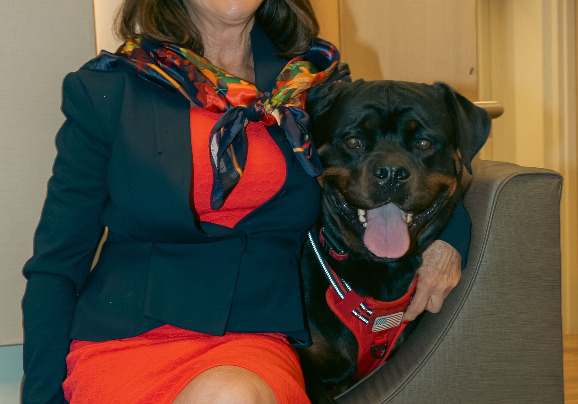 Woman sitting in a chair with a smile on her face, holding a dog in her arms