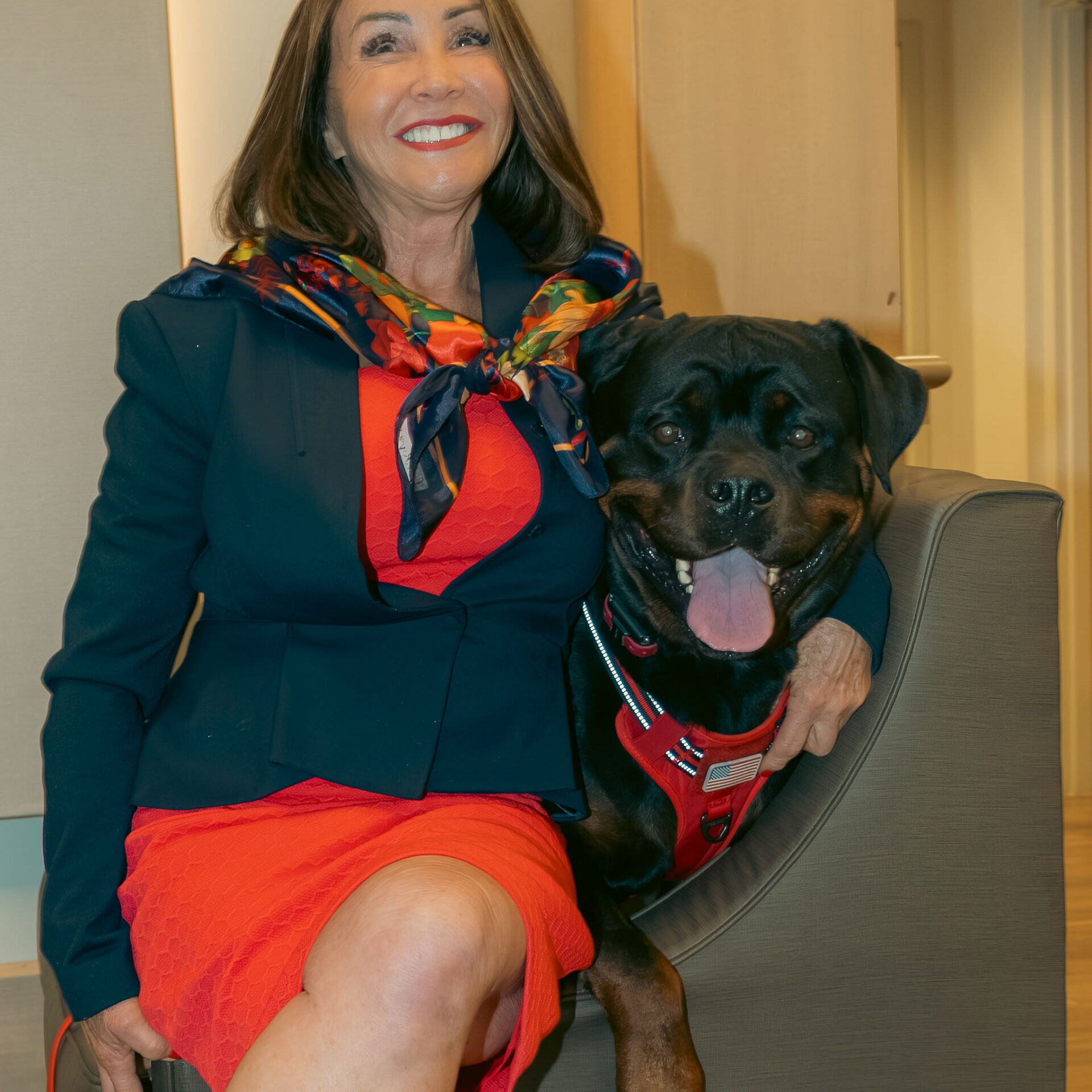 Woman sitting in a chair with a smile on her face, holding a dog in her arms