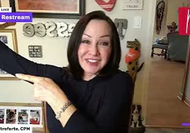 Woman in a shirt pointing at the camera with a smile on her face