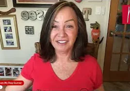 Woman in a shirt sitting at a table with a smile on her face
